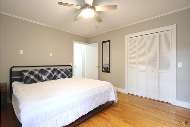 bedroom featuring light wood finished floors, baseboards, a ceiling fan, a closet, and ornamental molding