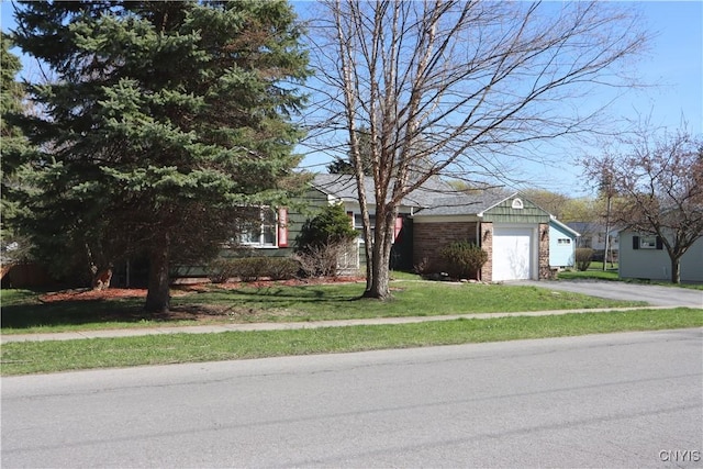 view of front facade with a front yard, driveway, a garage, and brick siding