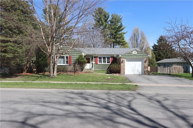 ranch-style house with a front lawn, driveway, a garage, and fence