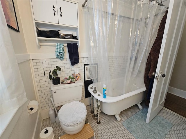 bathroom with shower / tub combo, toilet, a wainscoted wall, and tile walls