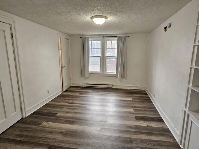 spare room featuring a baseboard heating unit, a textured ceiling, baseboards, and dark wood-style flooring