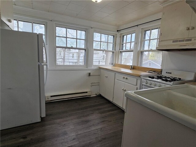 kitchen with a baseboard heating unit, dark wood finished floors, under cabinet range hood, and white appliances