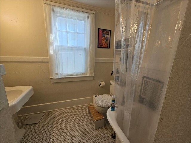 full bathroom featuring baseboards, curtained shower, ornamental molding, and toilet