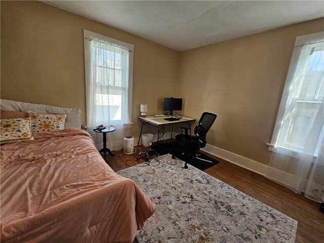 bedroom featuring dark wood-style flooring, baseboards, and multiple windows