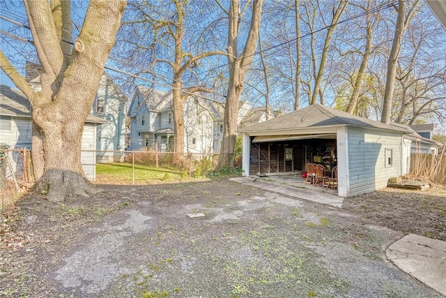 exterior space with fence, an outdoor structure, roof with shingles, and a garage