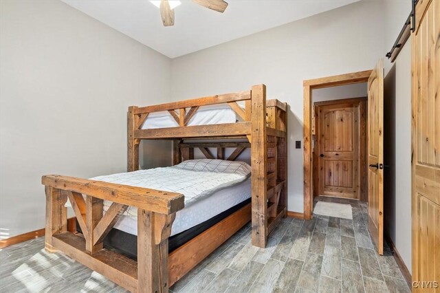 42795 Paynes Lake Camp Rd, Antwerp, NY 13608 - bedroom featuring a barn door, wood finished floors, a ceiling fan, and baseboards