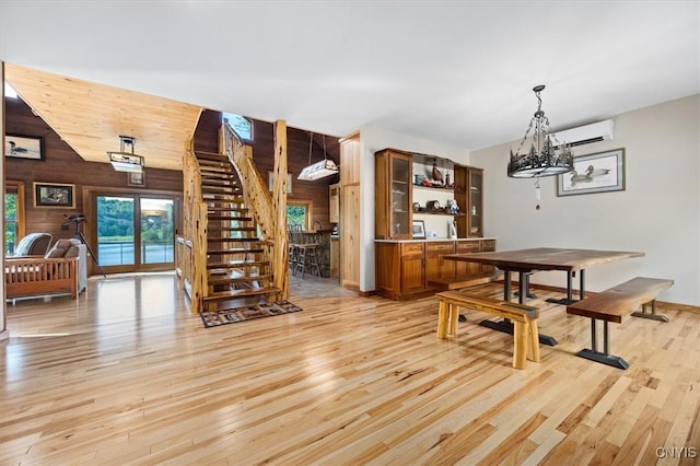 42795 Paynes Lake Camp Rd, Antwerp, NY 13608 - dining area with a wall mounted AC, stairs, wooden walls, and light wood-type flooring