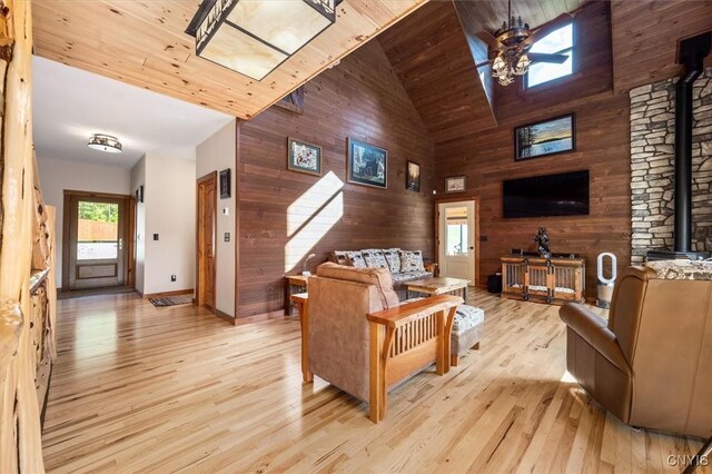 42795 Paynes Lake Camp Rd, Antwerp, NY 13608 - living area with wooden walls, a wood stove, a ceiling fan, and high vaulted ceiling