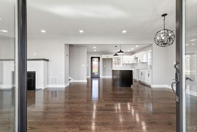 unfurnished living room with baseboards, a chandelier, and dark wood-type flooring