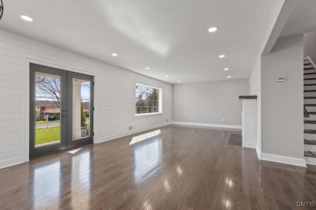 unfurnished living room featuring stairway, baseboards, wood finished floors, and french doors