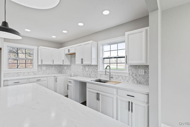 kitchen featuring white cabinets, backsplash, a sink, and recessed lighting