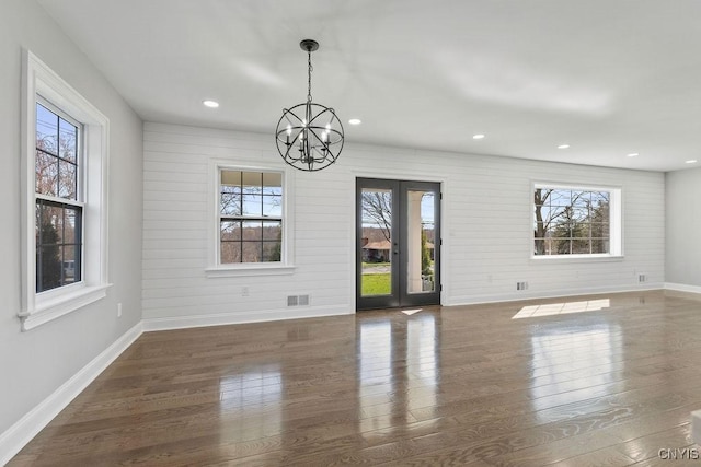 unfurnished dining area with baseboards, a healthy amount of sunlight, wood finished floors, and an inviting chandelier