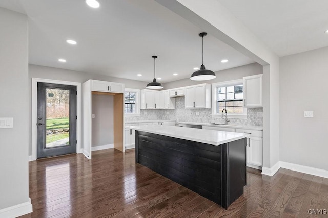 kitchen with plenty of natural light, a sink, backsplash, and white cabinetry