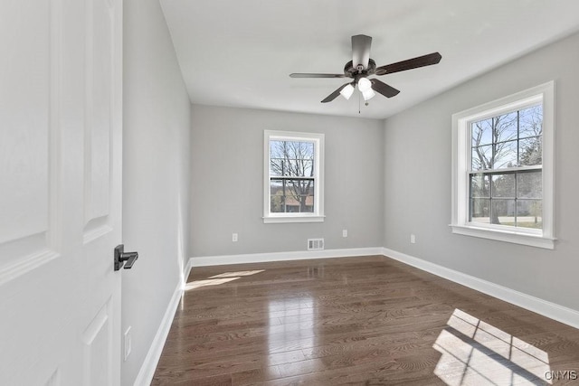 empty room with a ceiling fan, dark wood-style flooring, and a healthy amount of sunlight