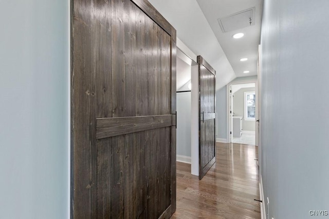 hallway featuring baseboards, lofted ceiling, wood finished floors, and recessed lighting