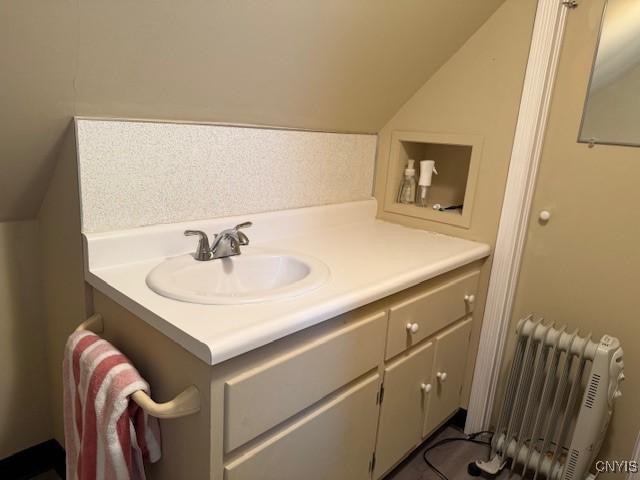 bathroom with vaulted ceiling, vanity, and radiator