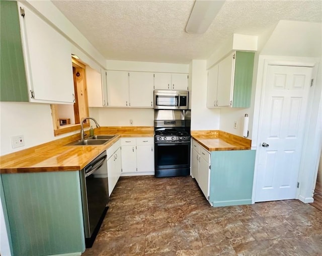 kitchen with butcher block countertops, a textured ceiling, stainless steel appliances, and a sink