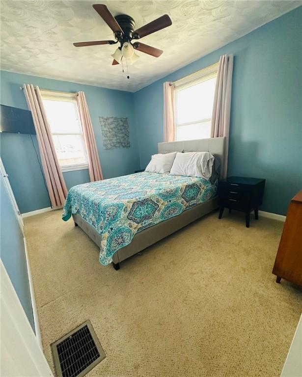 bedroom with visible vents, light carpet, baseboards, and multiple windows
