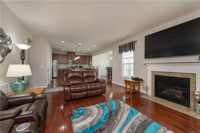living area with a fireplace, baseboards, dark wood-type flooring, visible vents, and recessed lighting