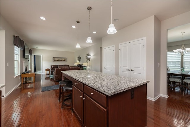 kitchen featuring baseboards, a kitchen island, pendant lighting, and dark wood-style floors