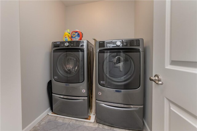 clothes washing area featuring washing machine and dryer, baseboards, and laundry area