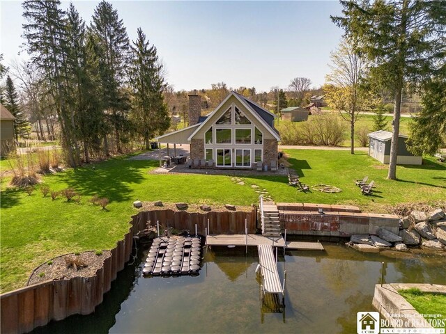 rear view of property featuring a chimney, an outdoor structure, a water view, and a yard