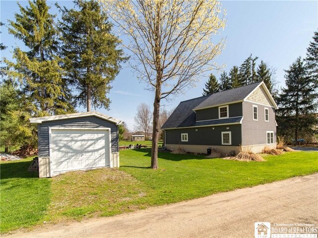 view of home's exterior featuring driveway, an outdoor structure, a yard, and a detached garage