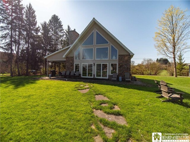 back of property featuring a lawn, stone siding, and a chimney