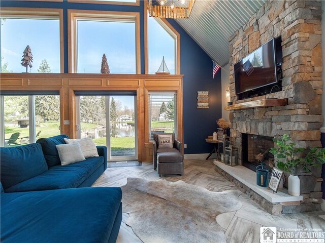 living area with a stone fireplace, a wealth of natural light, and high vaulted ceiling