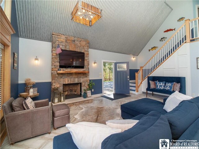 living room with a fireplace, a chandelier, stairway, and high vaulted ceiling