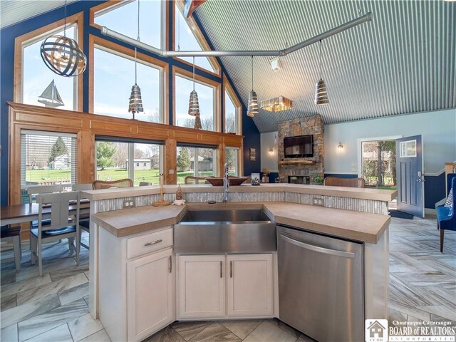 kitchen with a sink, open floor plan, high vaulted ceiling, dishwasher, and a fireplace