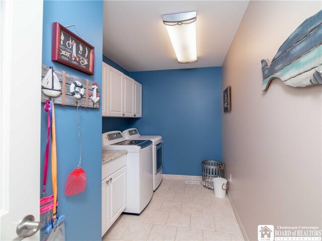 clothes washing area with baseboards, washing machine and clothes dryer, cabinet space, and light tile patterned floors