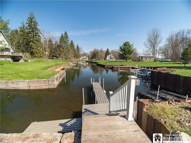 view of dock with a lawn and a water view