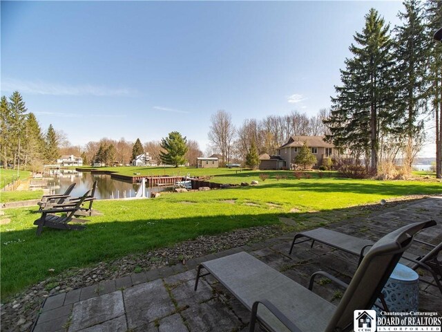 exterior space with a lawn, a patio area, and a water view