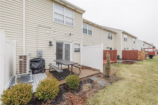 rear view of property with fence, a lawn, and a wooden deck