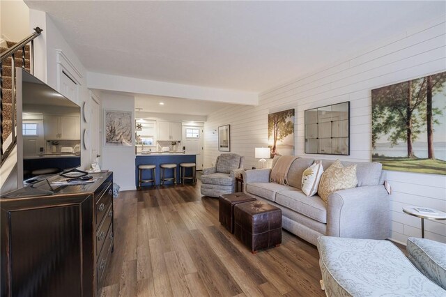 living room featuring dark wood finished floors, plenty of natural light, and wooden walls
