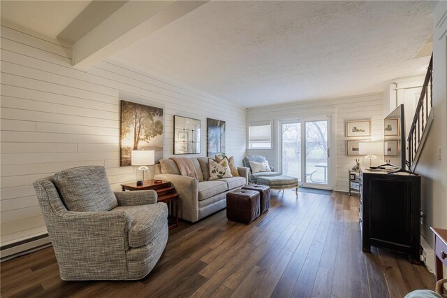 living room with wooden walls, beamed ceiling, a baseboard radiator, stairs, and dark wood-style flooring