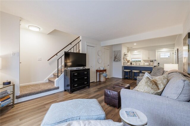 living area with baseboards, wood finished floors, and stairs