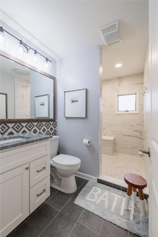 bathroom featuring a tile shower, toilet, tile patterned flooring, and visible vents