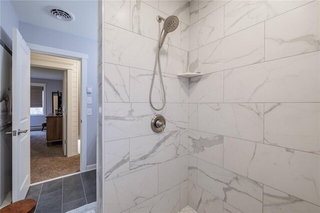 bathroom featuring visible vents, tiled shower, and baseboard heating