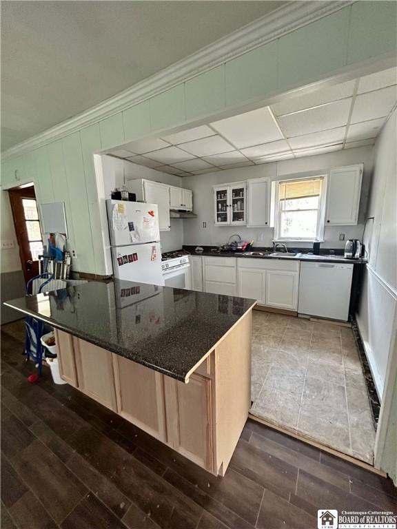 kitchen featuring white cabinets, ornamental molding, a sink, dark wood-type flooring, and white appliances