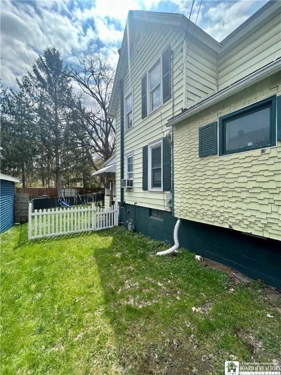view of property exterior with cooling unit, a lawn, and fence