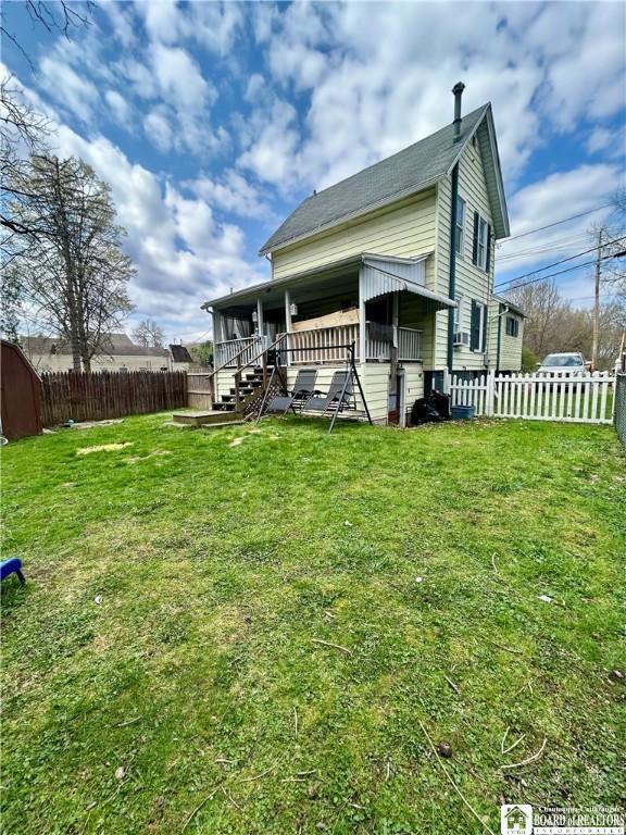 back of property featuring a yard, roof with shingles, and a fenced backyard