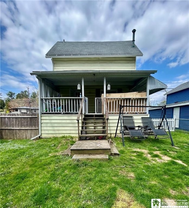 rear view of property with a yard, a shingled roof, and fence