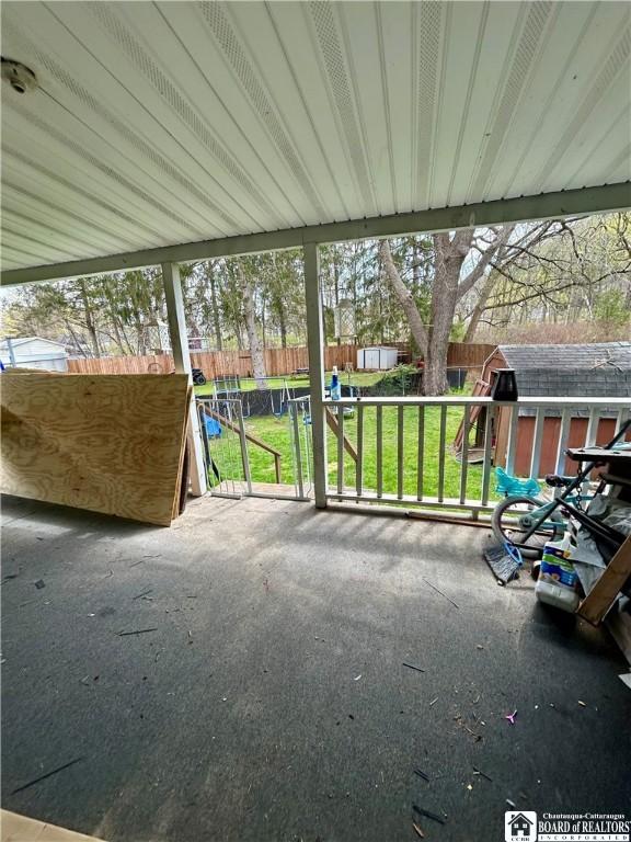 view of patio / terrace with a fenced backyard, an outdoor structure, and a storage unit
