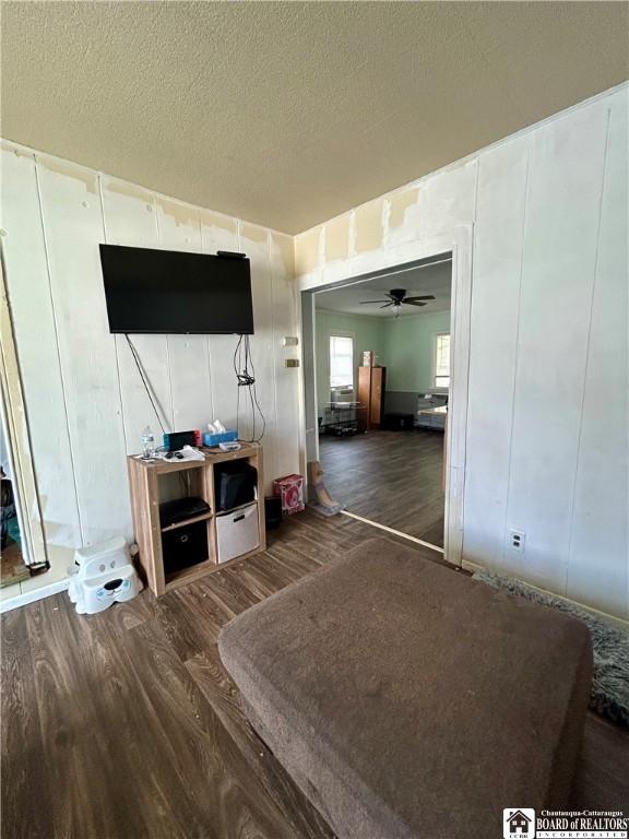 living area featuring a ceiling fan, wood finished floors, and a textured ceiling