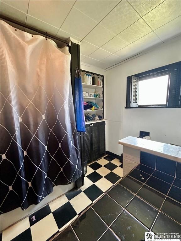 full bath featuring curtained shower and tile patterned floors