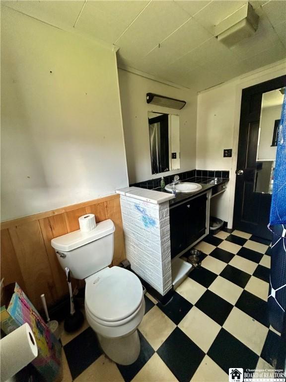 bathroom with wainscoting, tile patterned floors, vanity, and toilet