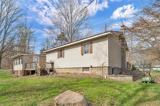 rear view of house with a chimney, a trampoline, and a lawn