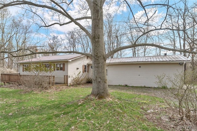 back of house with a lawn and metal roof